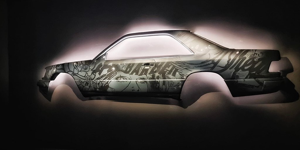 Œuvre street art de Ramzi Adek sur une carrosserie de voiture Mercedes suspendue, exposée à la Philharmonie de Paris avec éclairage dramatique.